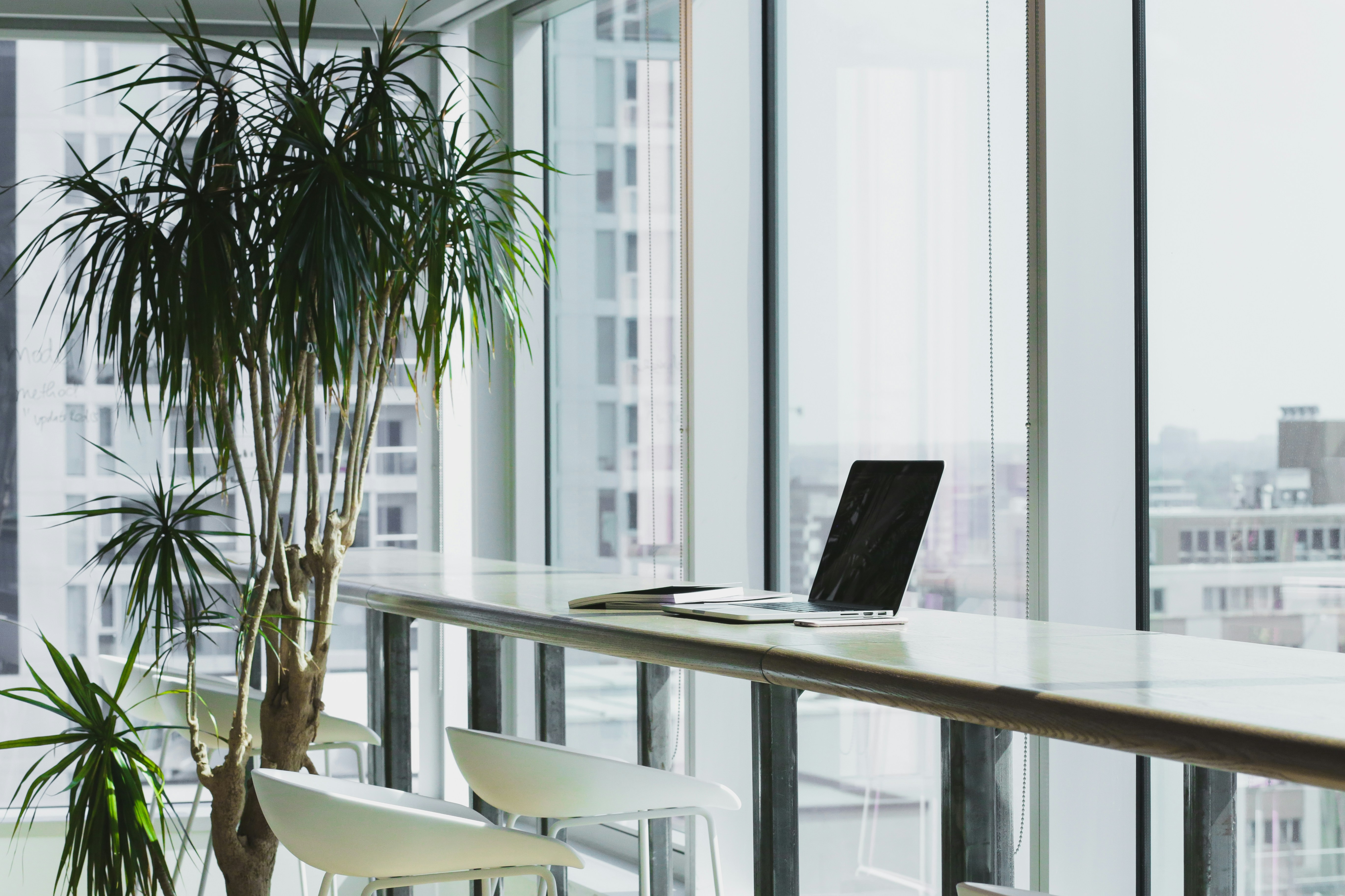slim laptop on a white table by the window in a bright office space