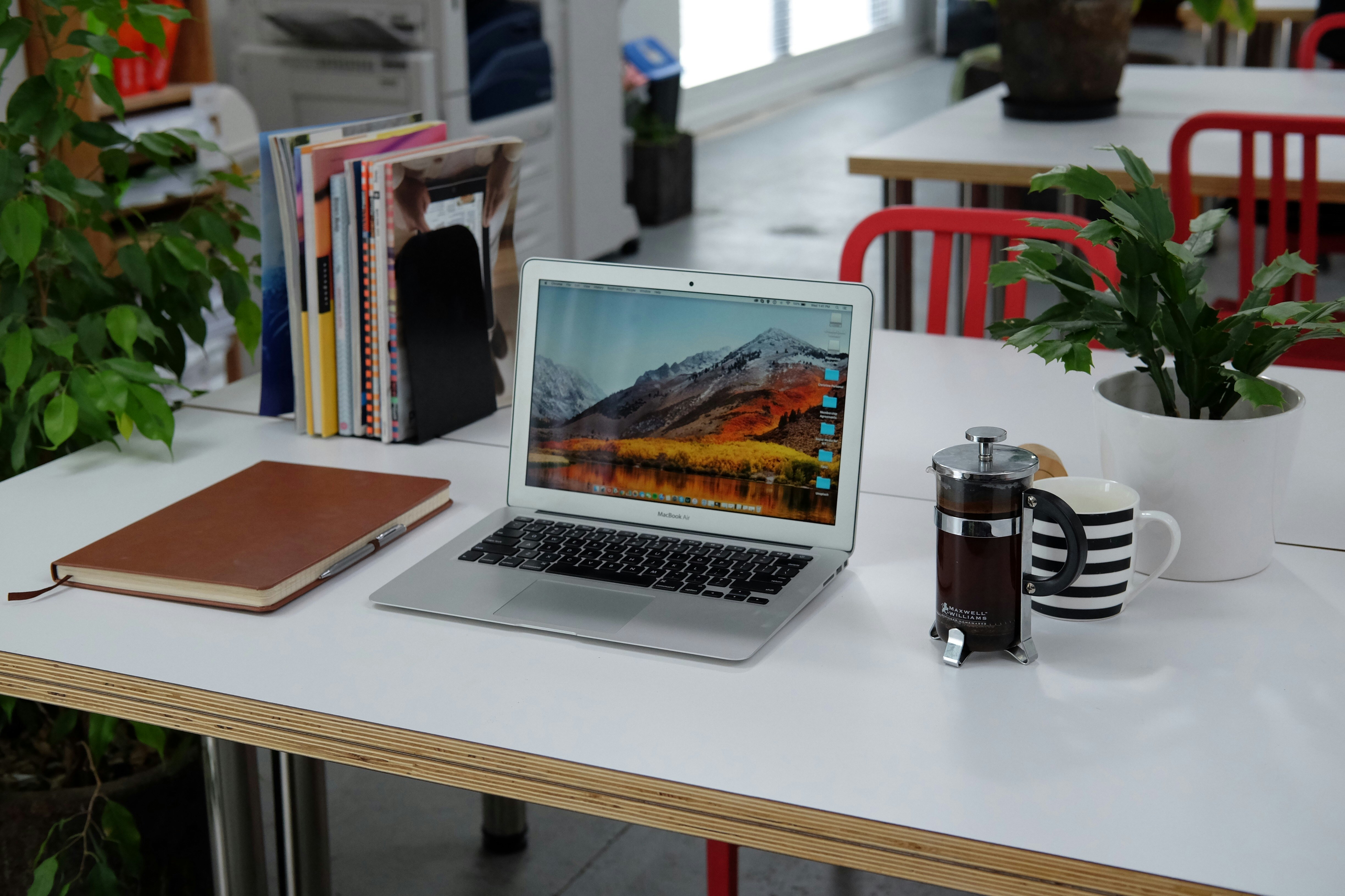 organized desk with laptop, books, notepad and coffee